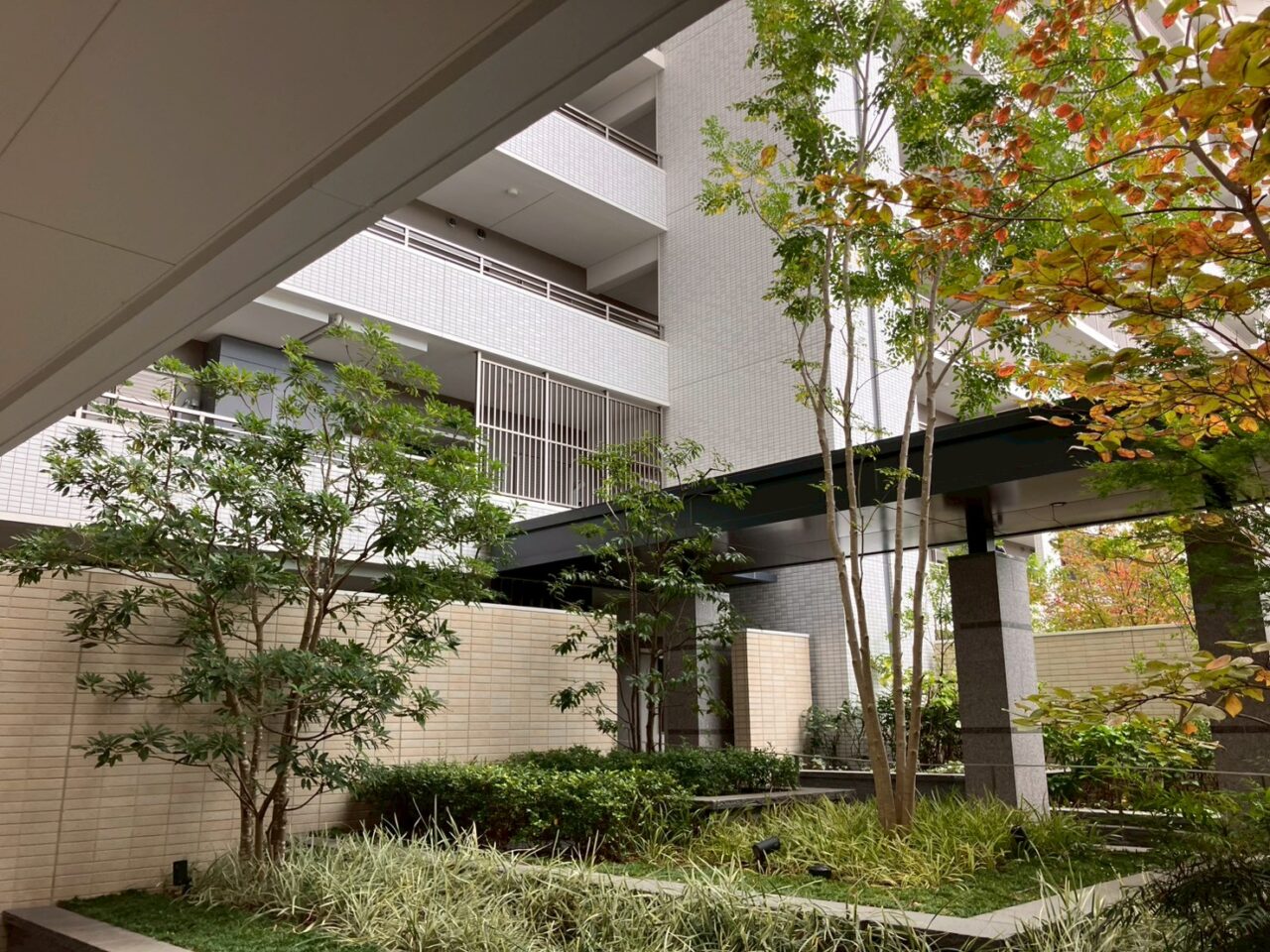 大阪府茨木市のマンション敷地内の植栽エリア。年間管理により整えられた中高木と低木が美しく配置されている様子。